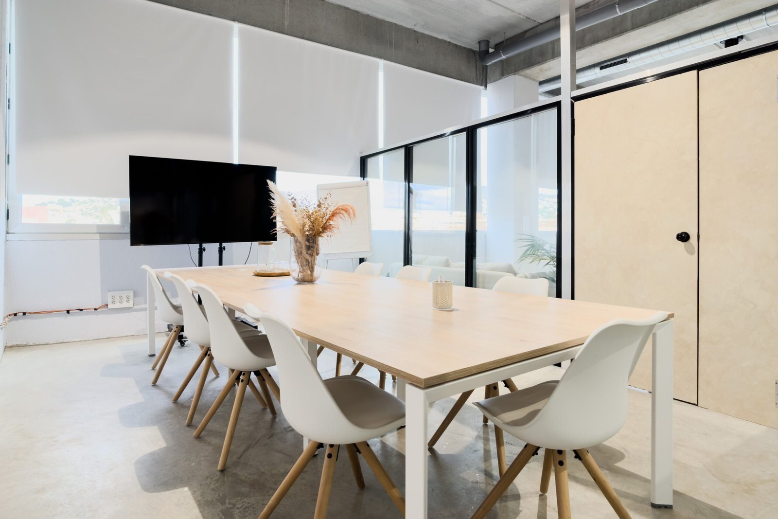 Sala de reuniones con mesa de madera y sillas blancas.